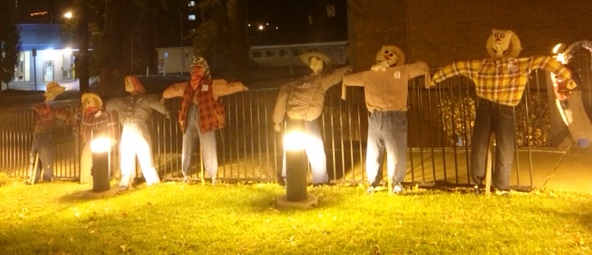 13 scarecrows lined up along the fence